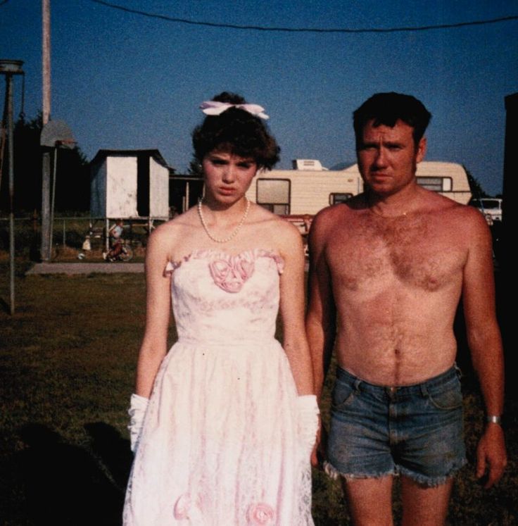 a man and woman standing next to each other in front of an rv park with no shirts on