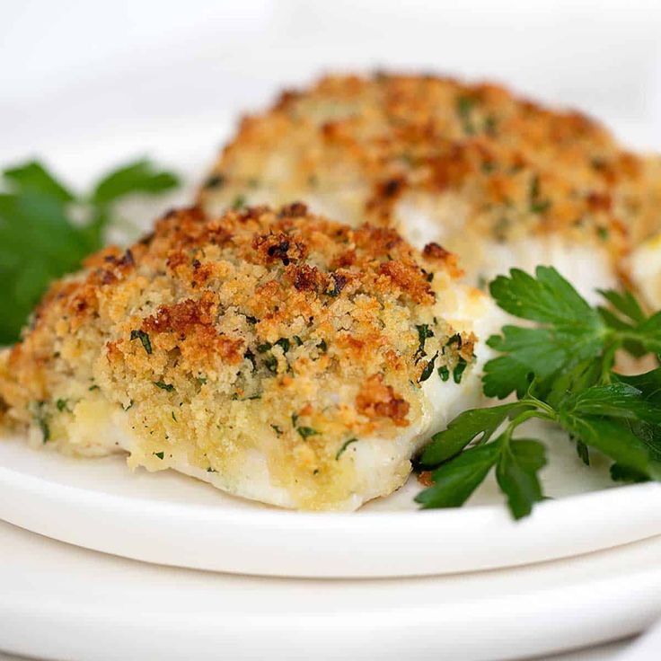 two pieces of chicken on a plate with parsley