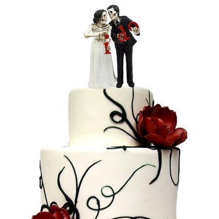 a wedding cake decorated with red flowers and skeleton figurines on top is shown