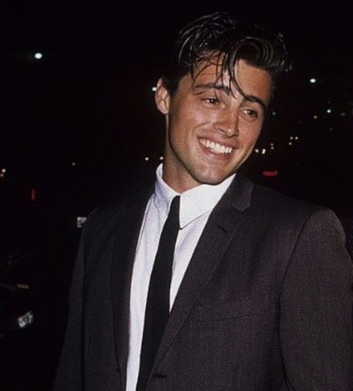 a man in a suit and tie smiling at the camera