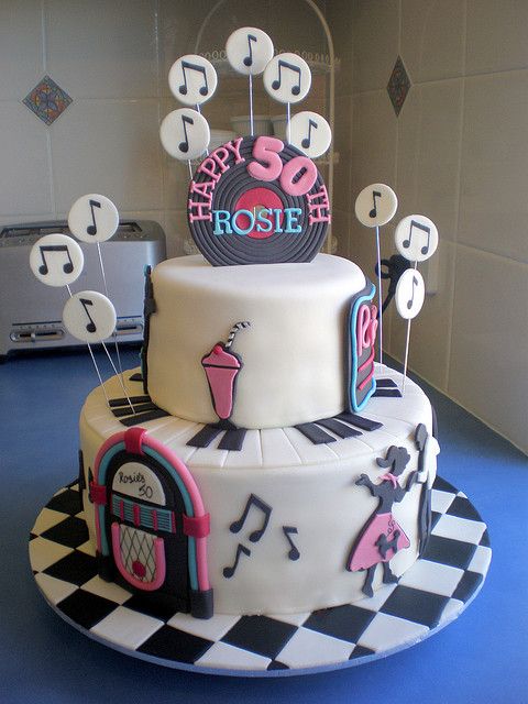 a three tiered cake decorated with music notes and musical symbols on top, sitting on a blue table