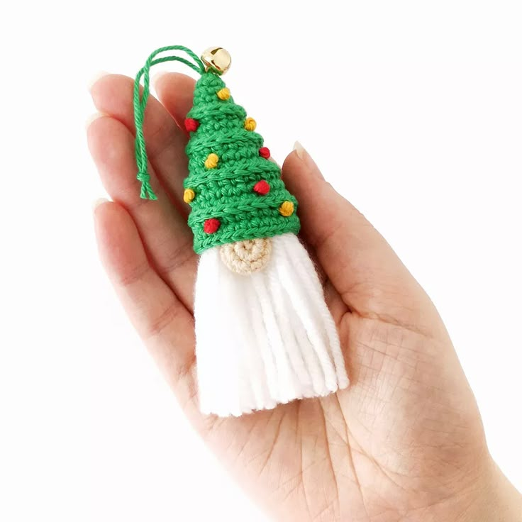 a crocheted christmas tree ornament in the palm of someone's hand