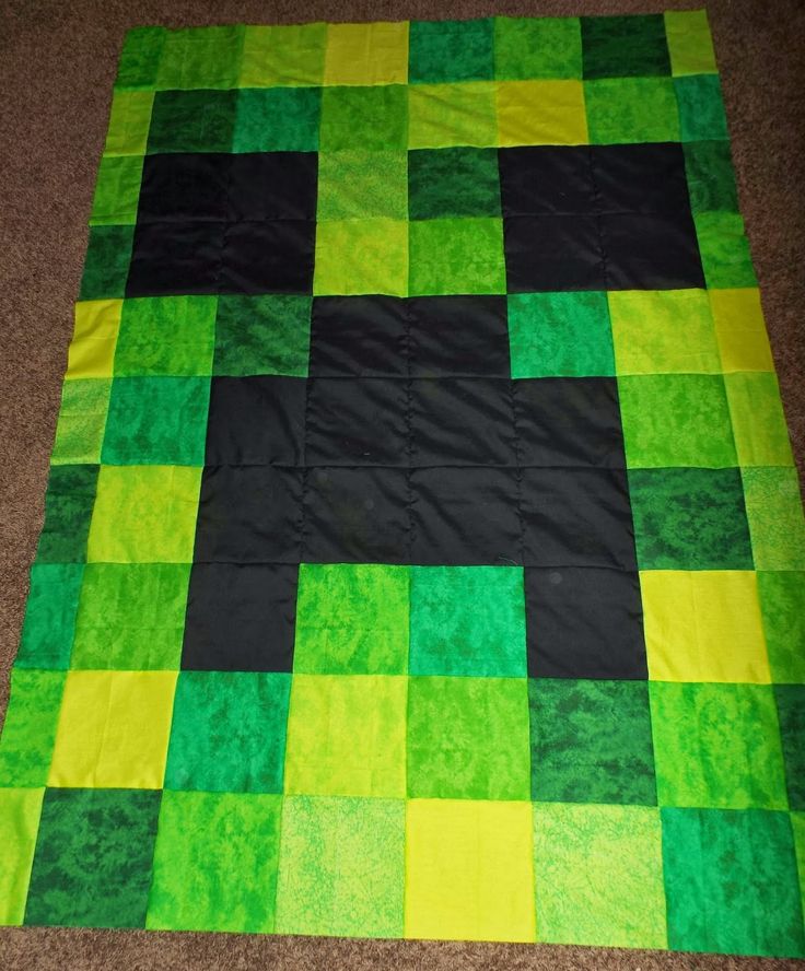 a green and black quilt is laying on the floor