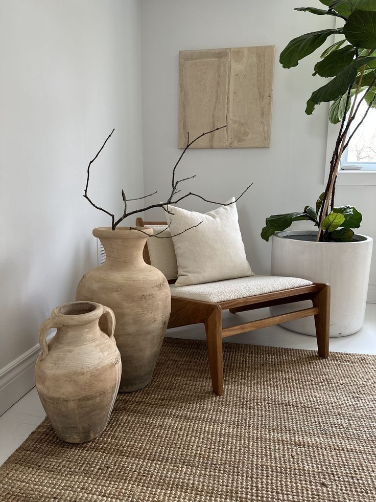 two large vases sitting on top of a rug next to a chair and potted plant