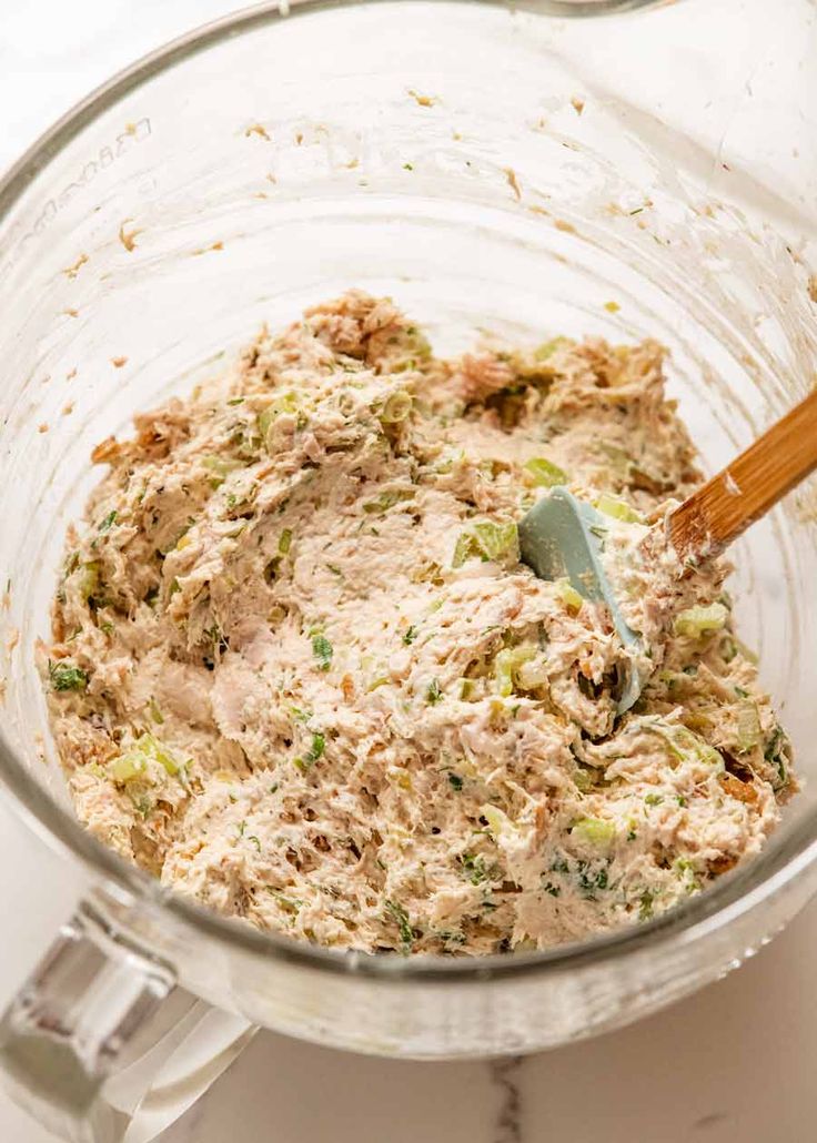 a glass bowl filled with food and a wooden spoon