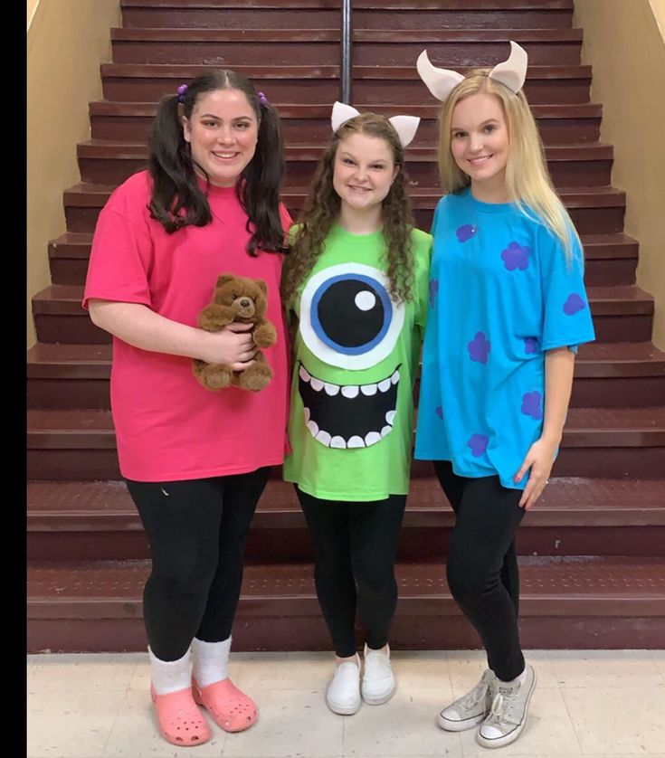 three girls in costumes standing next to each other on the stairs with their stuffed animals