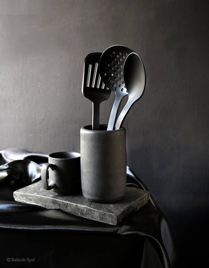 three spoons and two cups are sitting on a table with a black leather bag