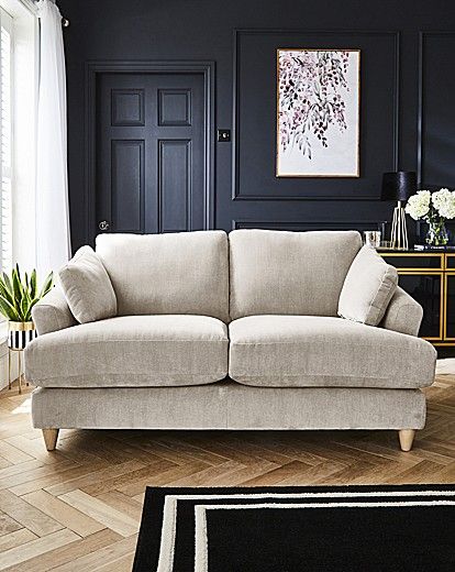 a living room with black walls and white furniture in the corner, along with a rug on the floor