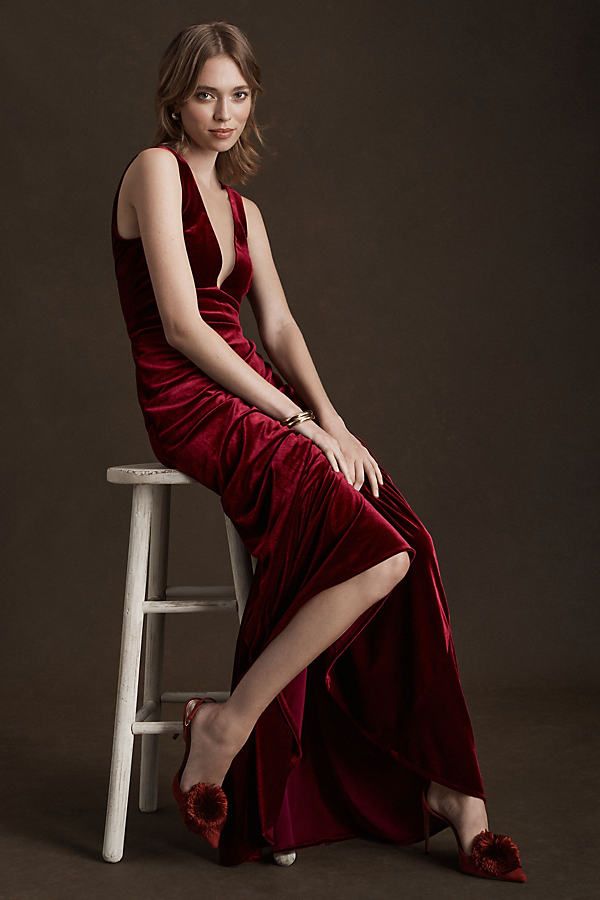 a woman in a red dress sitting on a stool