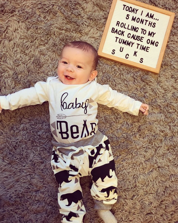 a baby is laying on the floor next to a sign