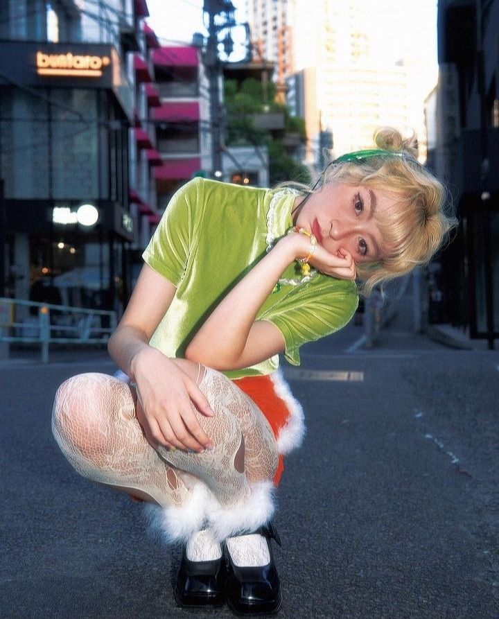 a woman kneeling down in the street with her hand on her face and legs crossed