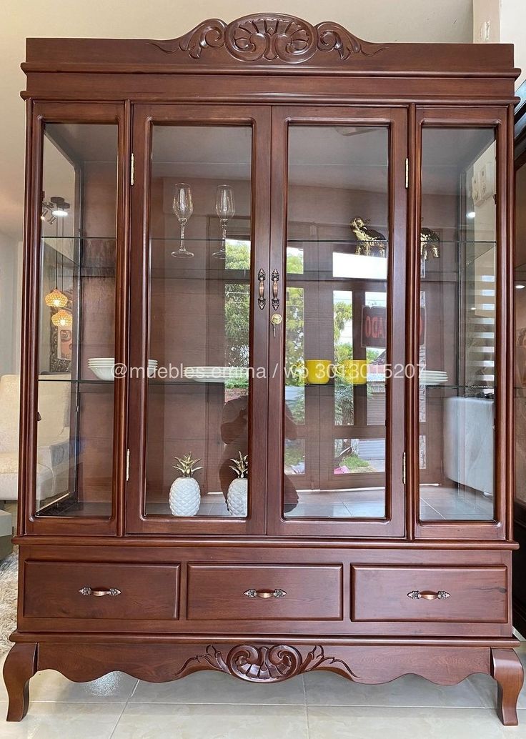 a wooden china cabinet with glass doors on the top and bottom, in a living room