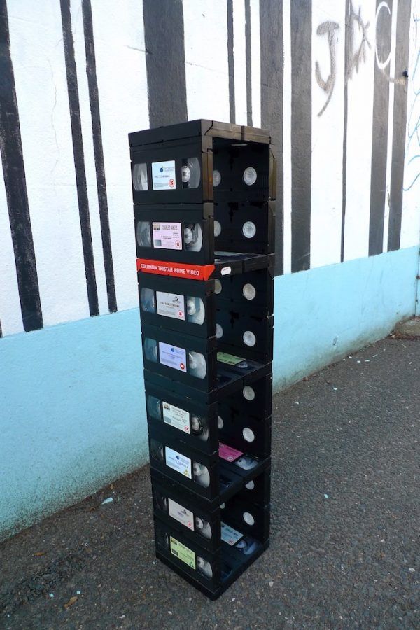 a stack of cassettes sitting on the side of a road next to a wall