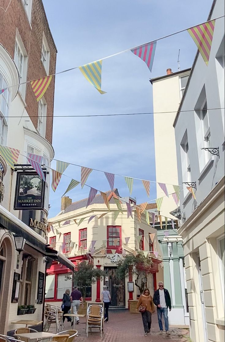 people are walking down the street in front of some buildings and flags flying above them