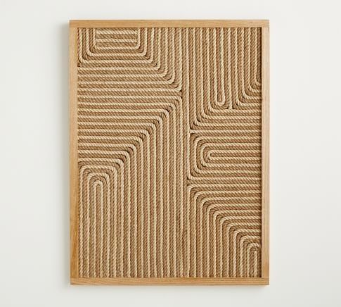 a woven wall hanging on a white wall with a wooden frame in the shape of a rectangle