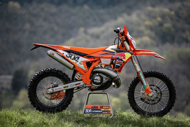 an orange dirt bike parked on top of a hill