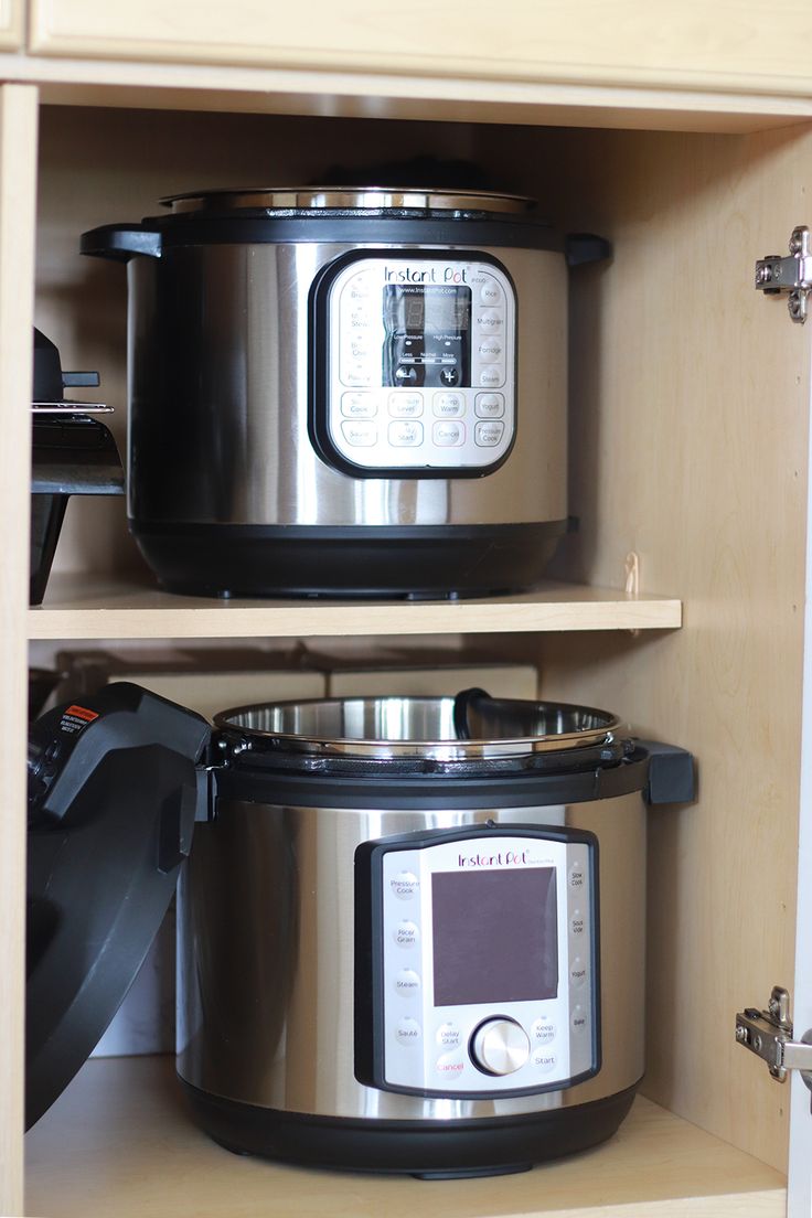 two crockpots sitting on top of each other in a cupboard next to an electric pressure cooker