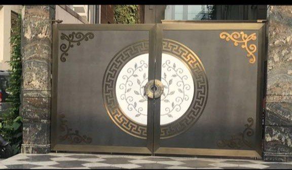 a large metal gate with an intricate design on the front and side doors, in front of a building