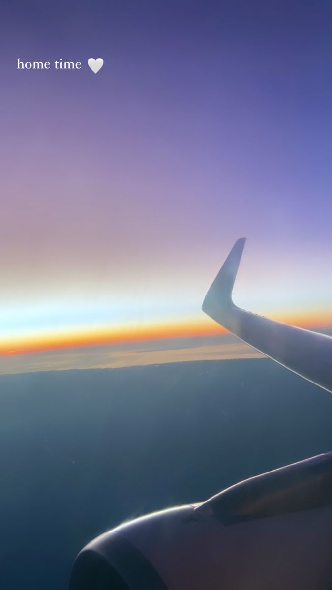 the wing of an airplane as it flies over the ocean and land at sunset or dawn