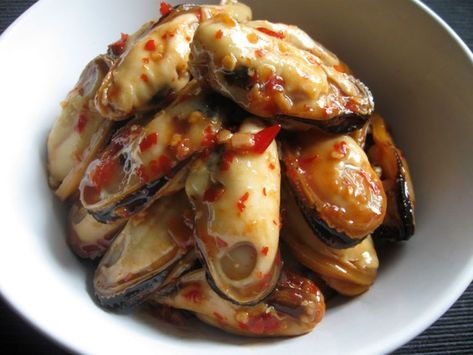 a white bowl filled with cooked clams covered in marinara sauce on top of a wooden table