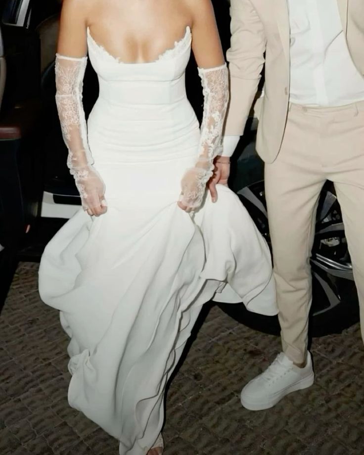 a man in a suit and tie standing next to a woman in a white dress