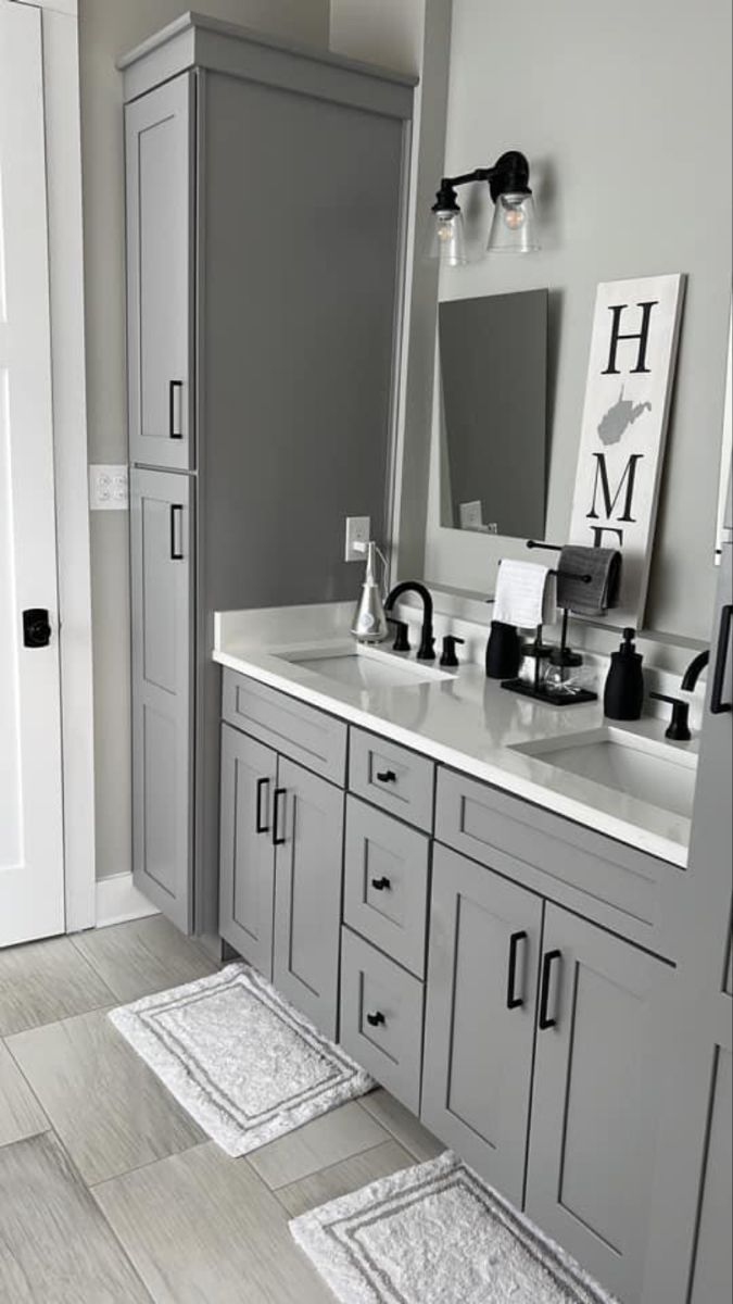 a bathroom with gray cabinets and white counter tops