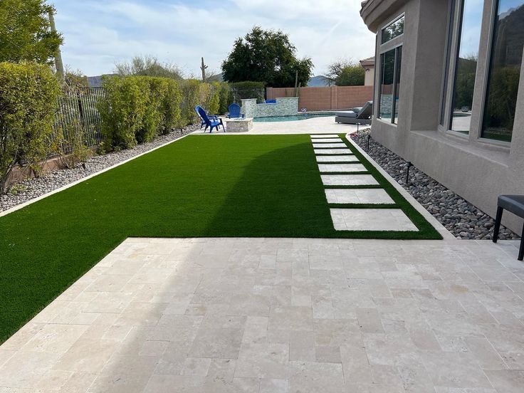 an outdoor patio with artificial grass and stepping stones