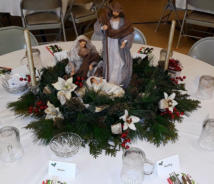 the table is set for christmas with candles and figurines on top of it