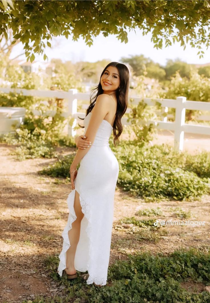 a woman in a white dress standing under a tree