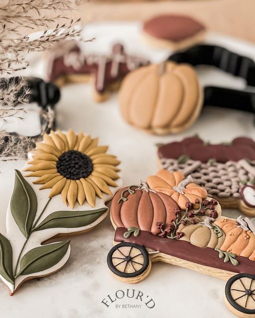 decorated cookies are sitting on a plate with flowers and leaves in the background, including sunflowers