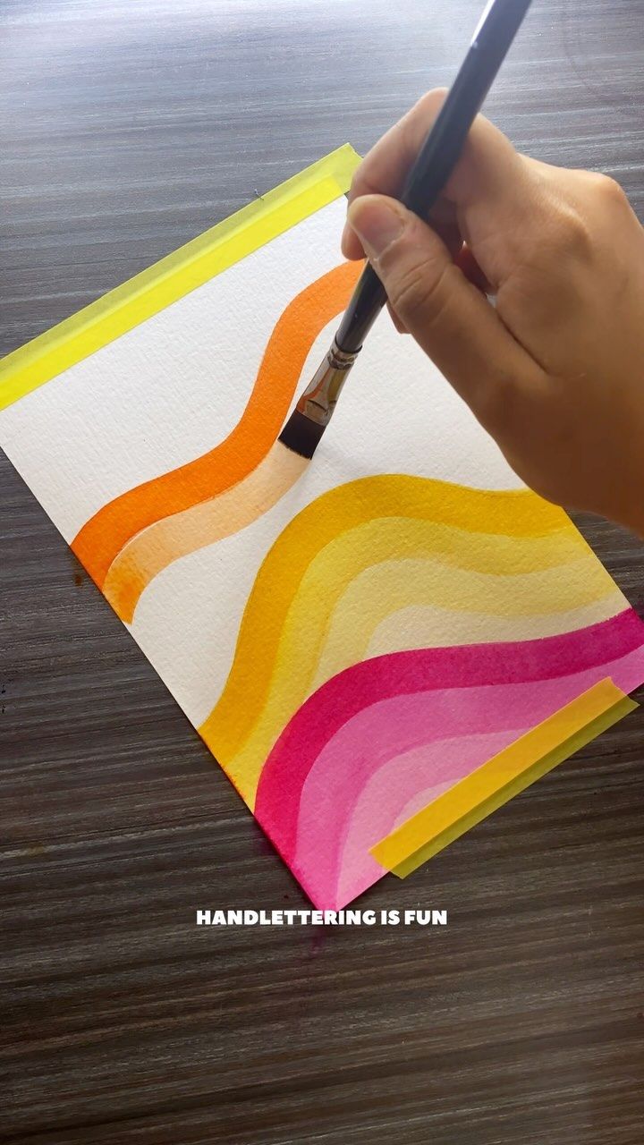 a person is holding a pencil and drawing on paper with watercolors in it