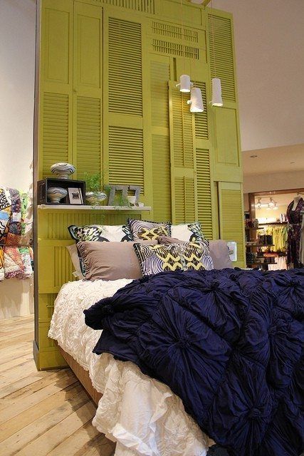 a bedroom with green shutters on the wall and blue bedding in front of it