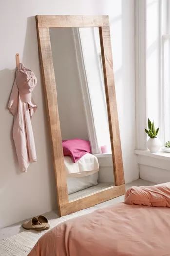 a bedroom with a large mirror on the wall and a pink bed in front of it