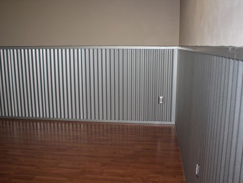 an empty room with hard wood floors and striped walls