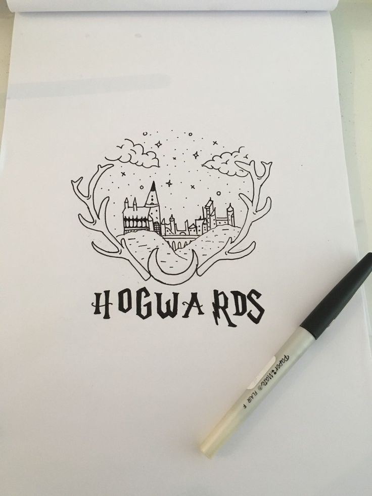 a pen sitting on top of a piece of paper next to a drawing pad with hogwarts written on it