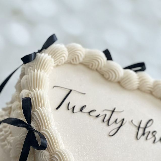 there is a white cake with black ribbon on the top that says, twenty firsts