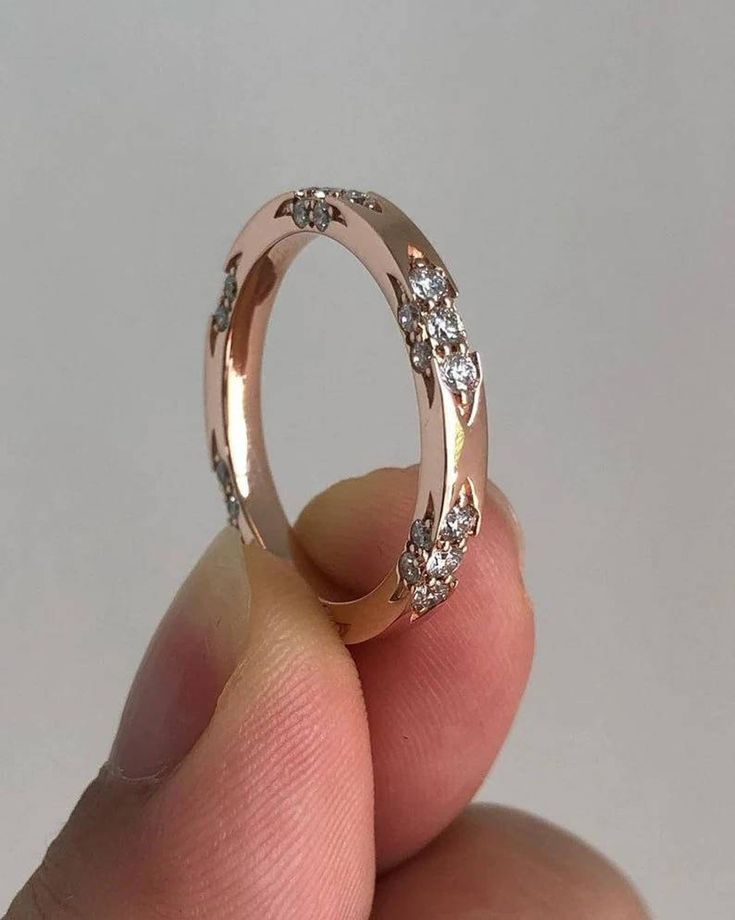 someone is holding a wedding ring with diamonds on the inside and outside, in front of a white background