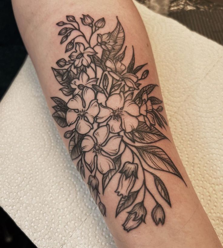 a black and white flower tattoo on the left arm, with flowers in it's center