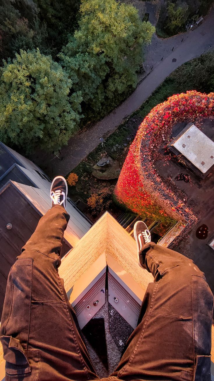 a person standing on top of a roof with their feet in the air and looking down