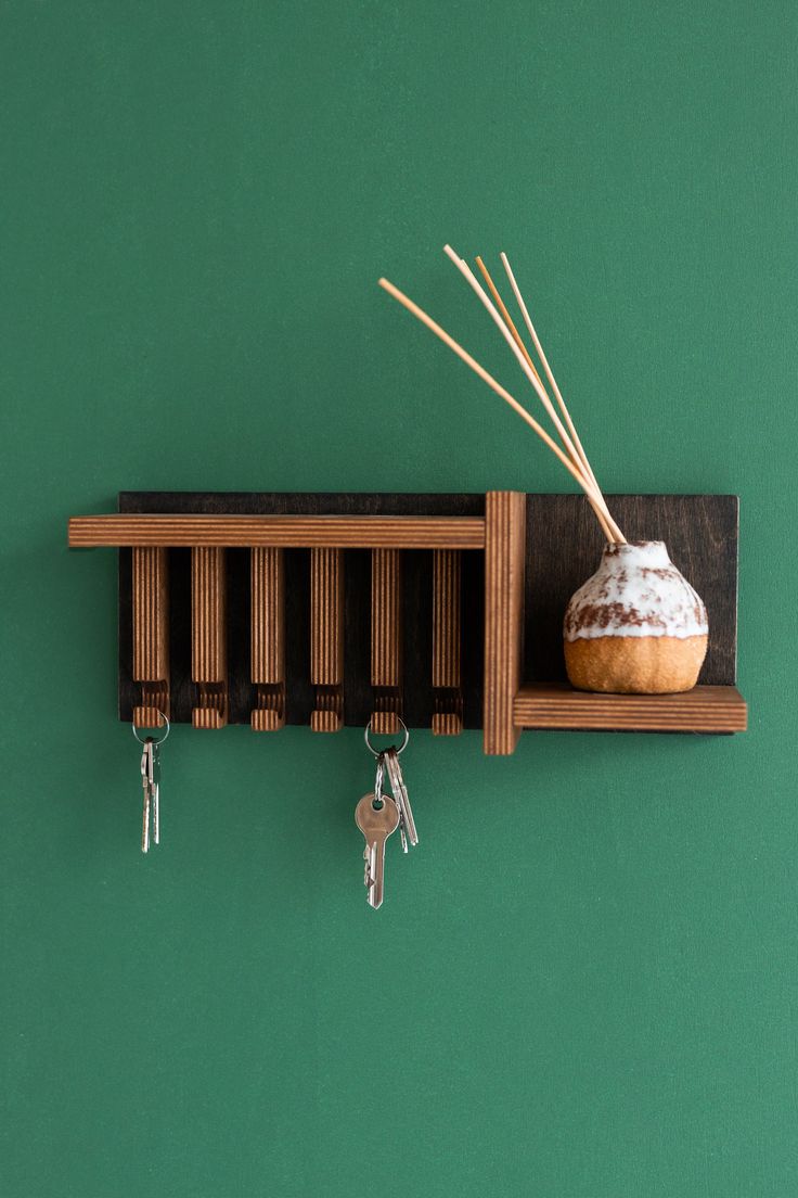 a wooden shelf with key hooks and a vase on it, hanging from the wall