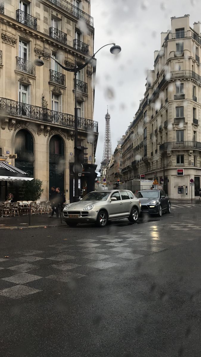 two cars are parked on the street in front of some buildings and an eiffel tower