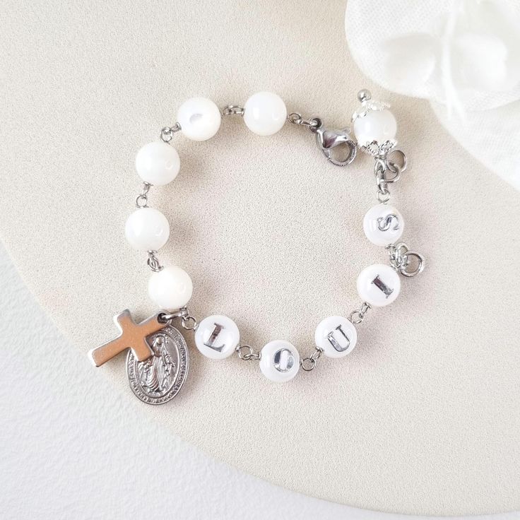 This stunning Baptism bracelet is a truly divine piece that combines elegance and spiritual significance. Crafted with natural mother of pearl beads, it features gold plated virgin Mary and cross charms that symbolize protection and faith. The bracelet is personalized with a handcrafted initial letter, adding a unique touch to this meaningful piece. Perfect for commemorating a special occasion or as a thoughtful gift, this bracelet is a beautiful reminder of faith and blessings. *MATCHING ROSARY Baptism Bracelet, Baby Girl Boy, Communion Gifts, Holy Communion, Initial Letter, Cross Charms, Birthday Present, Virgin Mary, Birthday Presents