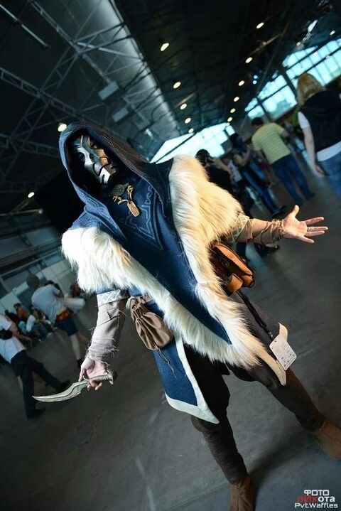 a person in costume is walking through an indoor area with other people and one has his arms out