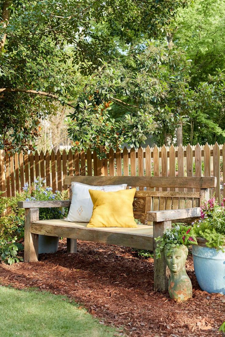 a wooden bench sitting in the middle of a garden with potted plants around it