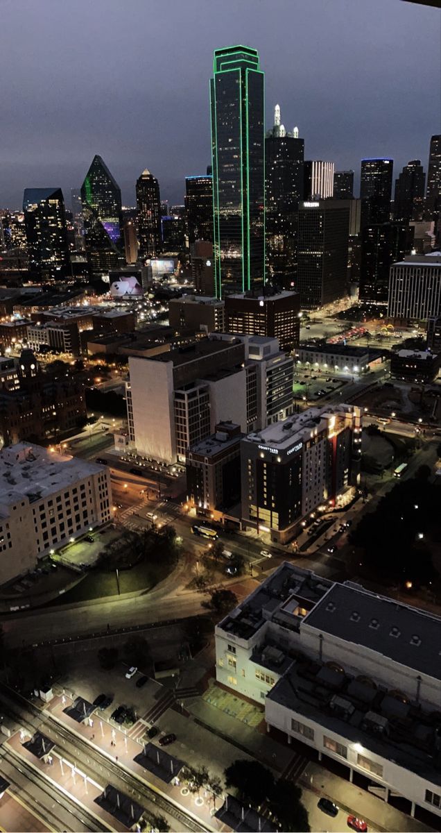 an aerial view of a city at night with skyscrapers lit up in the background