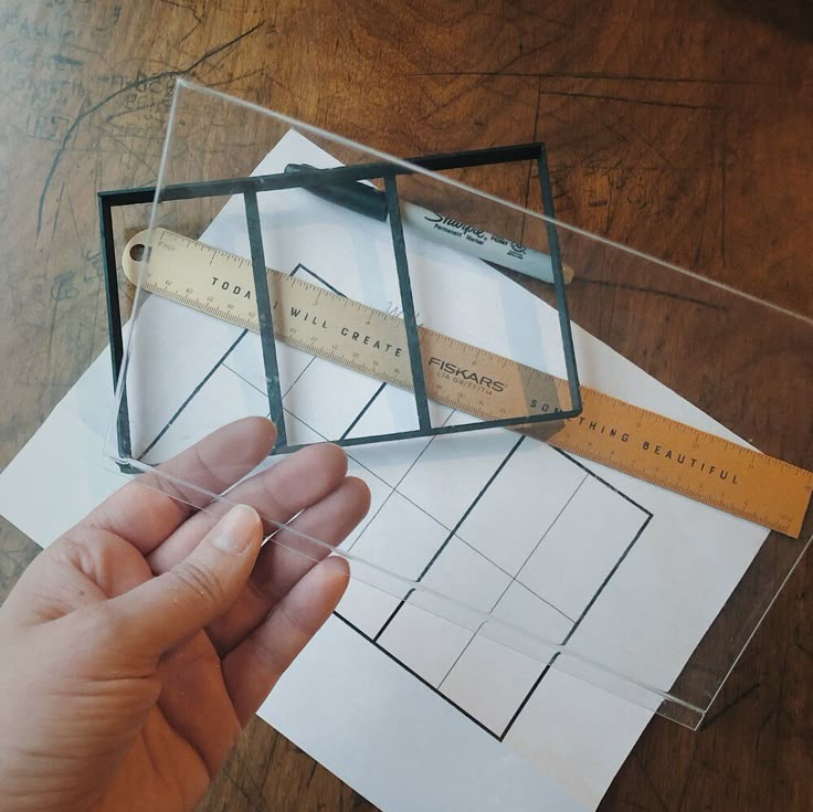 a person is holding a ruler in a box on top of some papers and paper