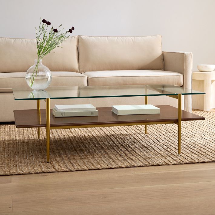 a glass coffee table sitting on top of a wooden floor next to a white couch