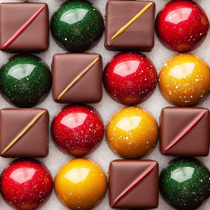 many different colored chocolates in a box with candy sticks sticking out of one side