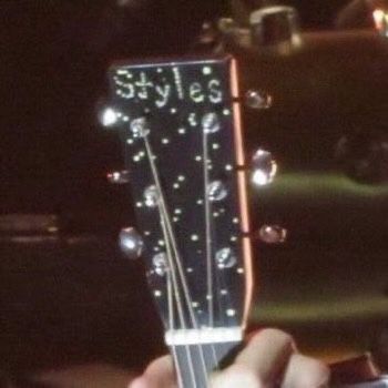 a person holding an acoustic guitar in their right hand and looking at the strings on it