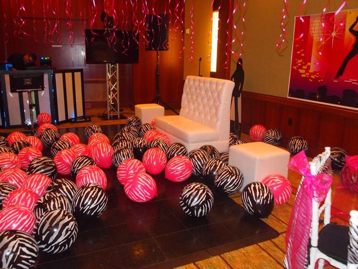 a room filled with lots of zebra print balls on the floor and balloons hanging from the ceiling